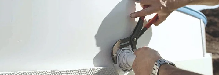 Person montiert Pool-Düse mit Zange.